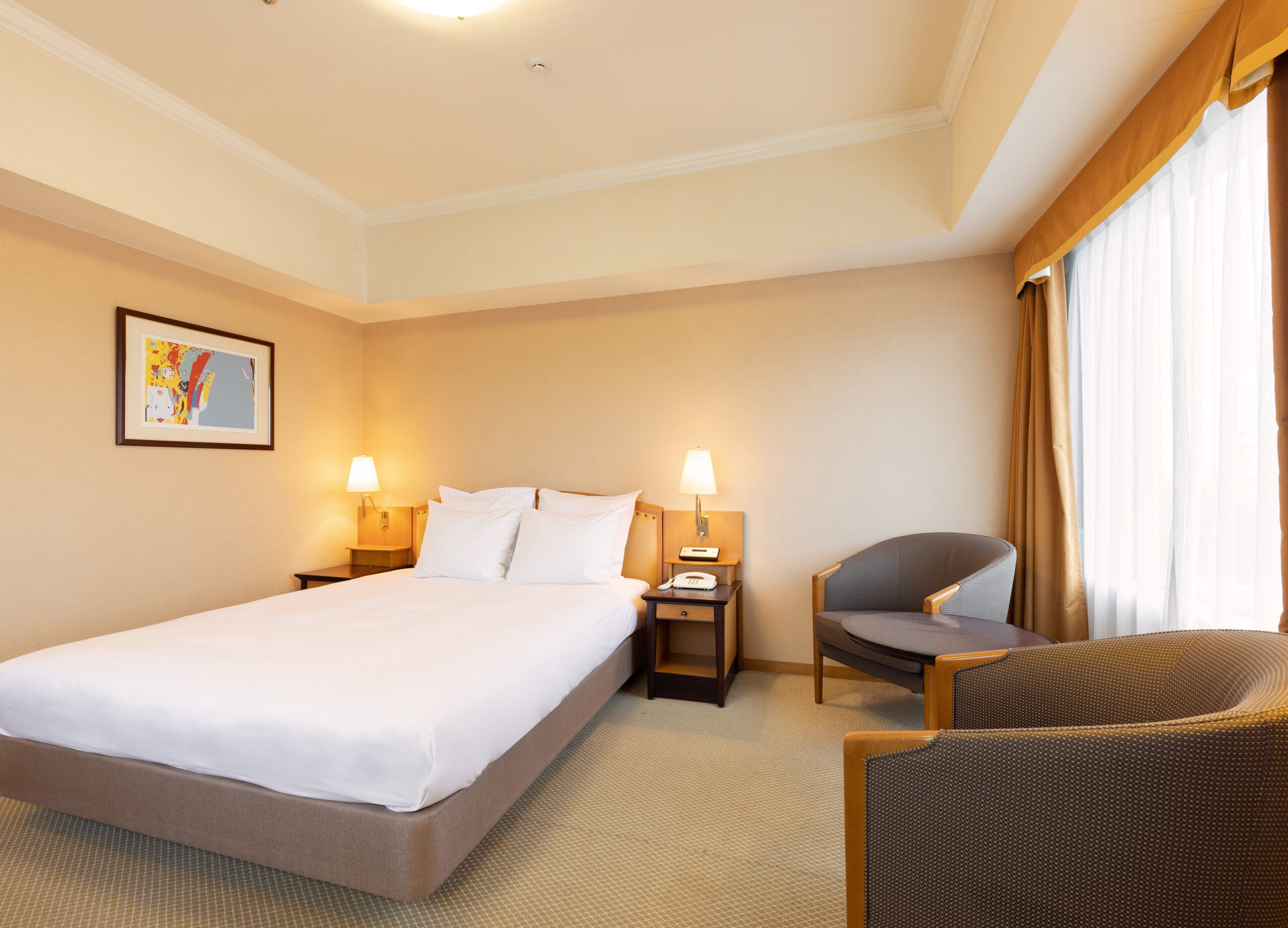 A hotel room with a large bed, two bedside tables with lamps, a chair, and a painting on the wall.