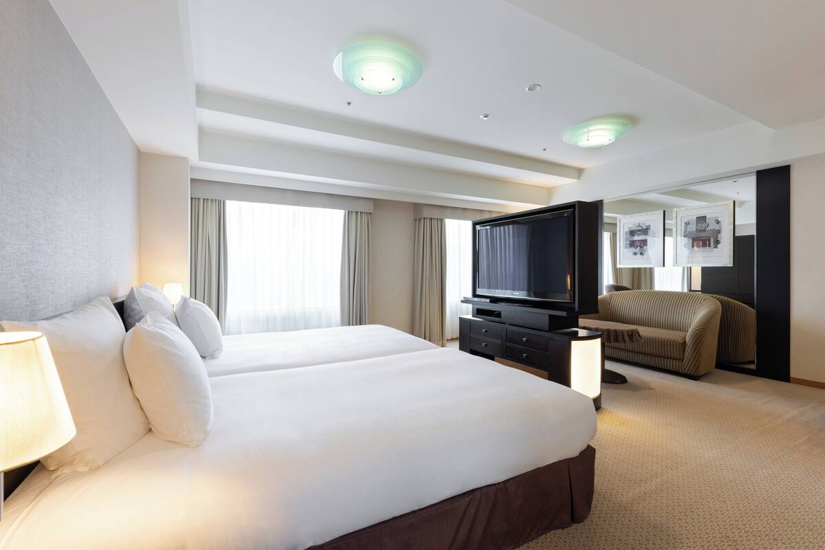Una habitación de hotel con una cama grande, televisión, sofá y escritorio.