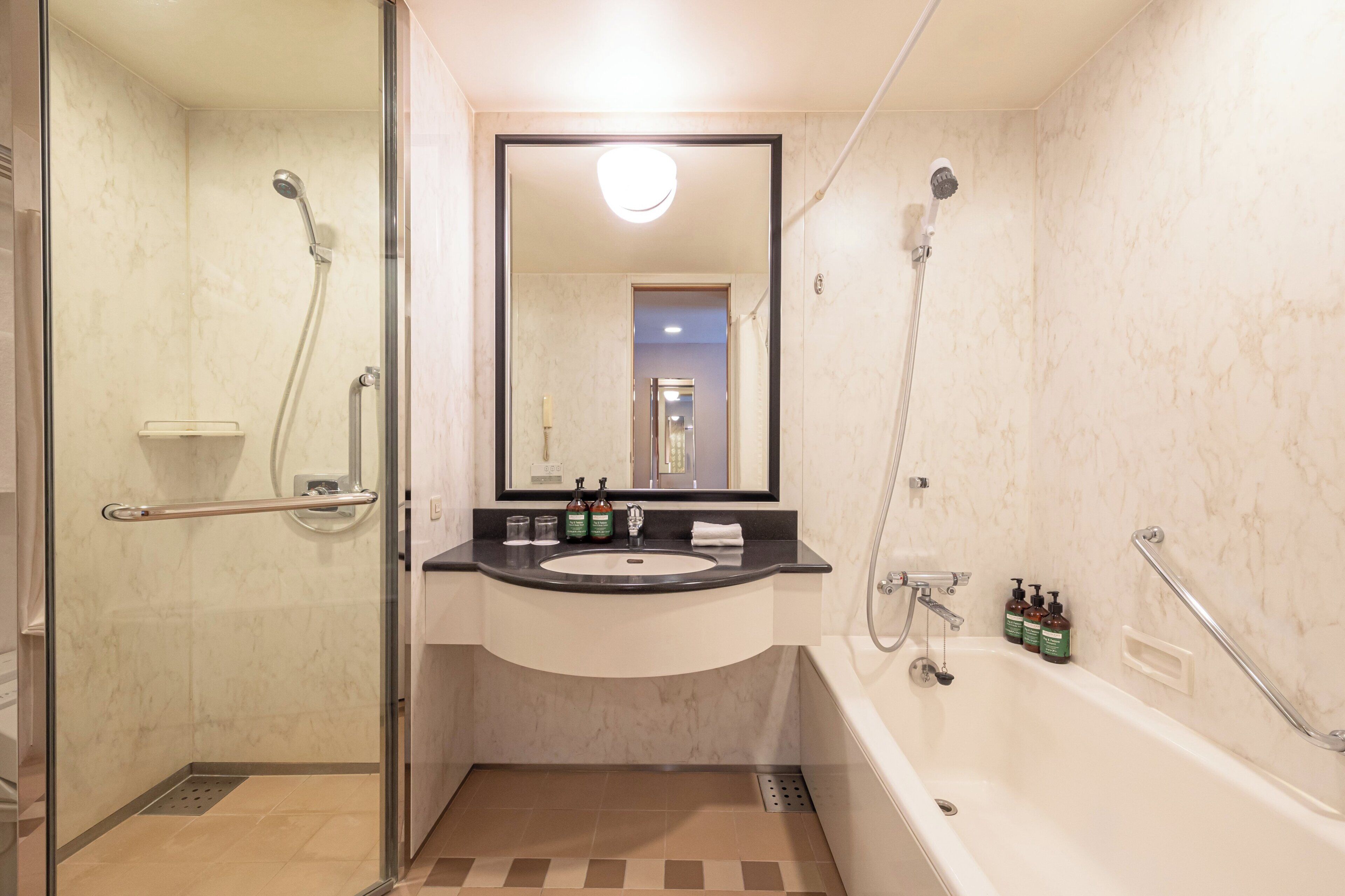 A bathroom with a glass shower enclosure, a sink with a mirror, and a bathtub.