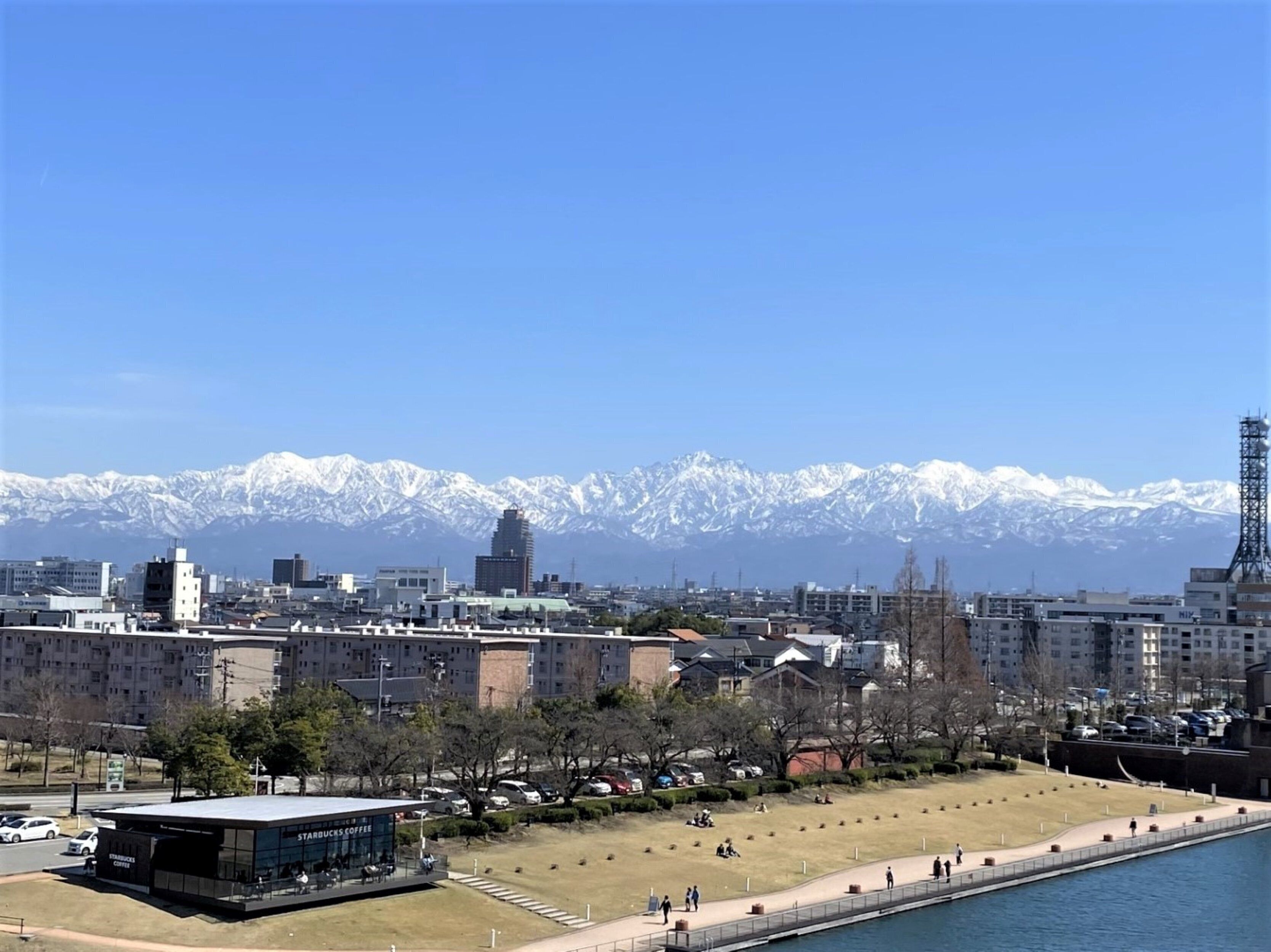A cityscape with a Starbucks, a river, and snow-capped mountains in the background.