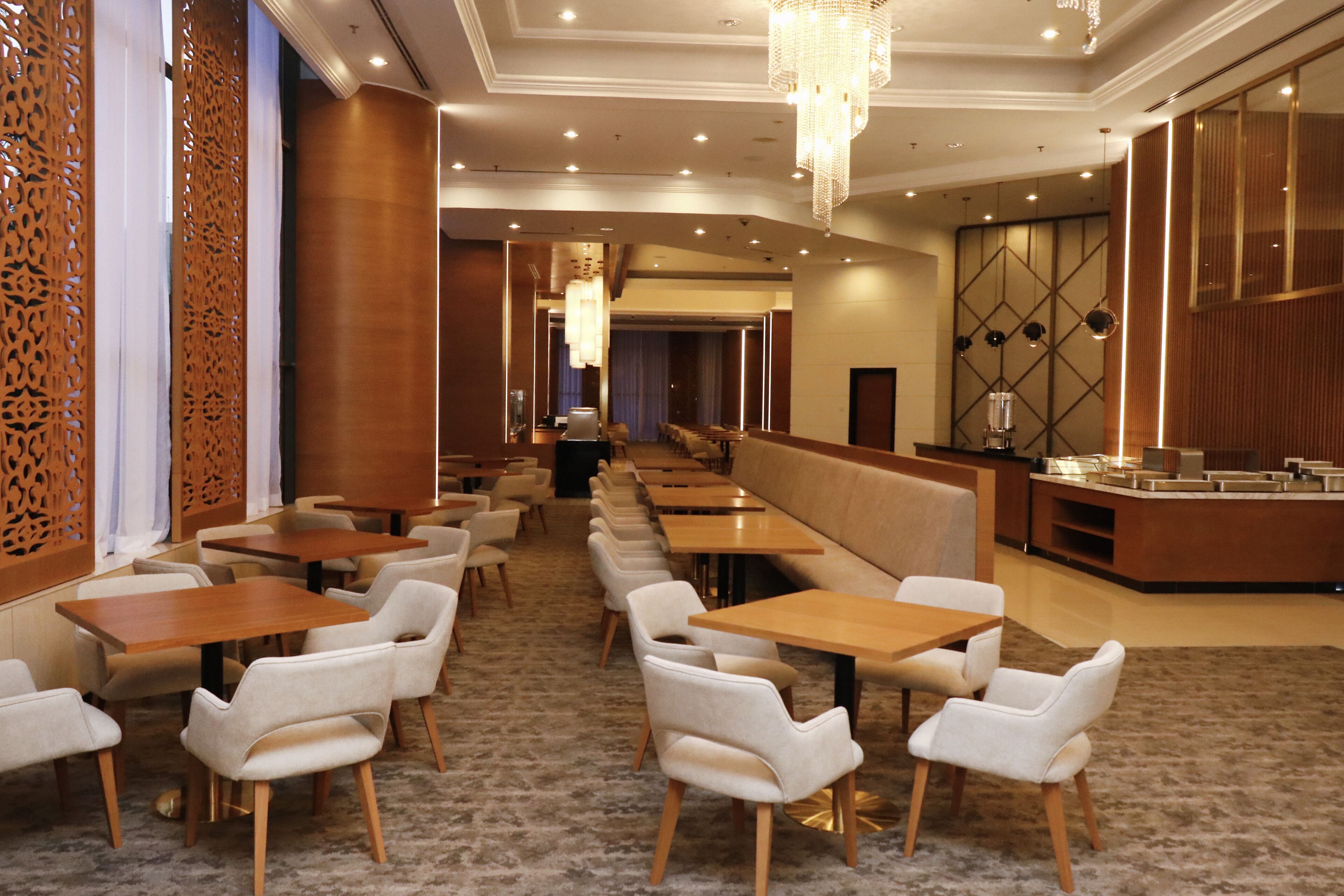 A hotel dining area with long tables, cushioned booths, and a buffet counter.