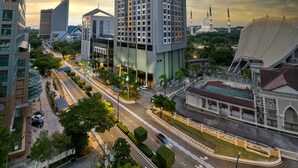 A modern hotel with a prominent entrance, surrounded by a well-maintained urban environment, including a mosque and a distinctive building with a unique roof design. - Mardhiyyah Hotel and Suites (Shah Alam)