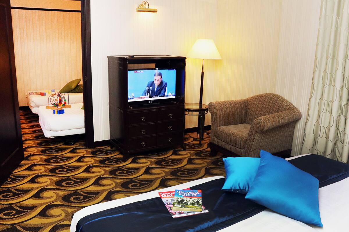 Ein Hotelzimmer mit Bett, Fernseher, Sofa und Lampe.