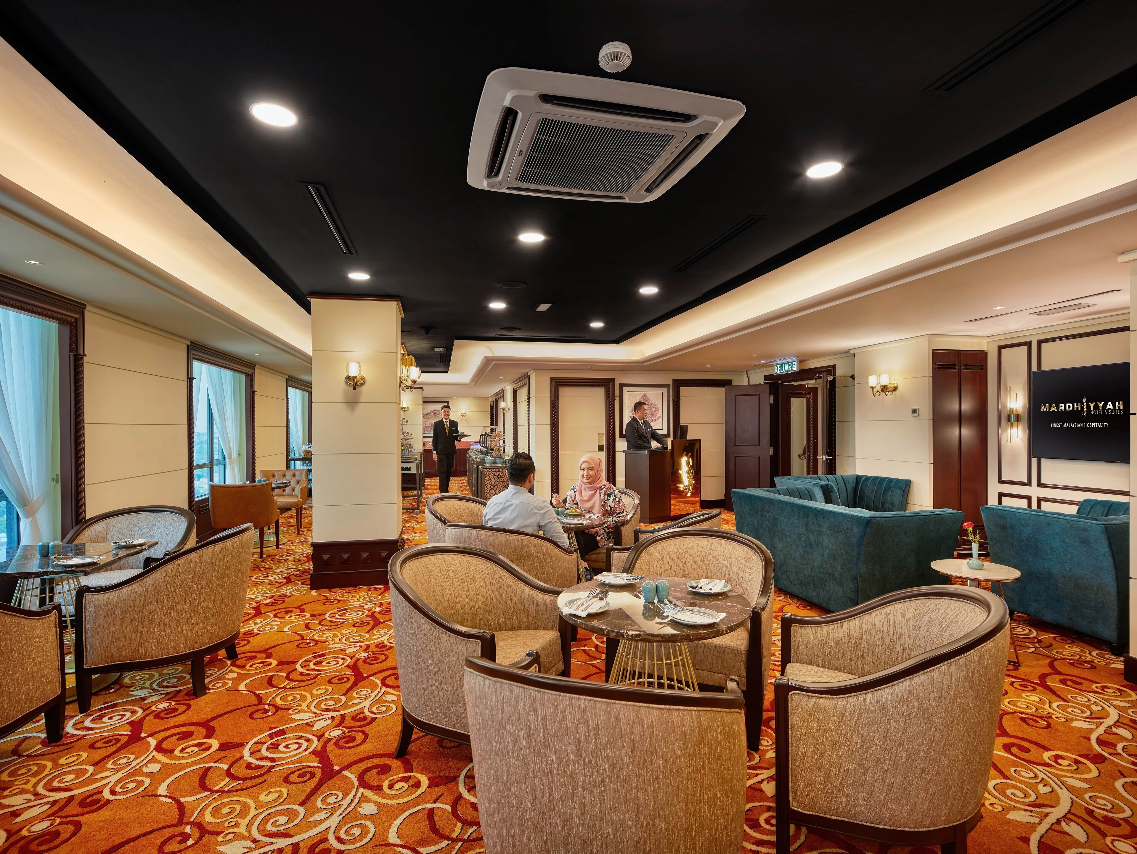 Eine Hotelhalle mit einem gemusterten Teppich, Sitzbereichen und einer Rezeption.