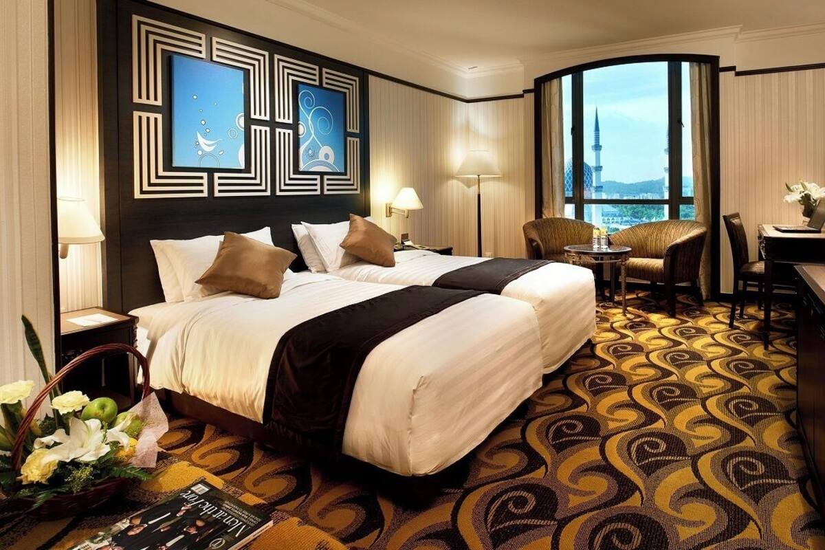 Ein Hotelzimmer mit einem großen Bett, einem Schreibtisch, einem Stuhl und Blick auf eine Stadtlandschaft.