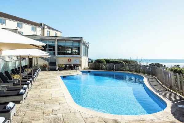 Una piscina al aire libre de temporada, sombrillas