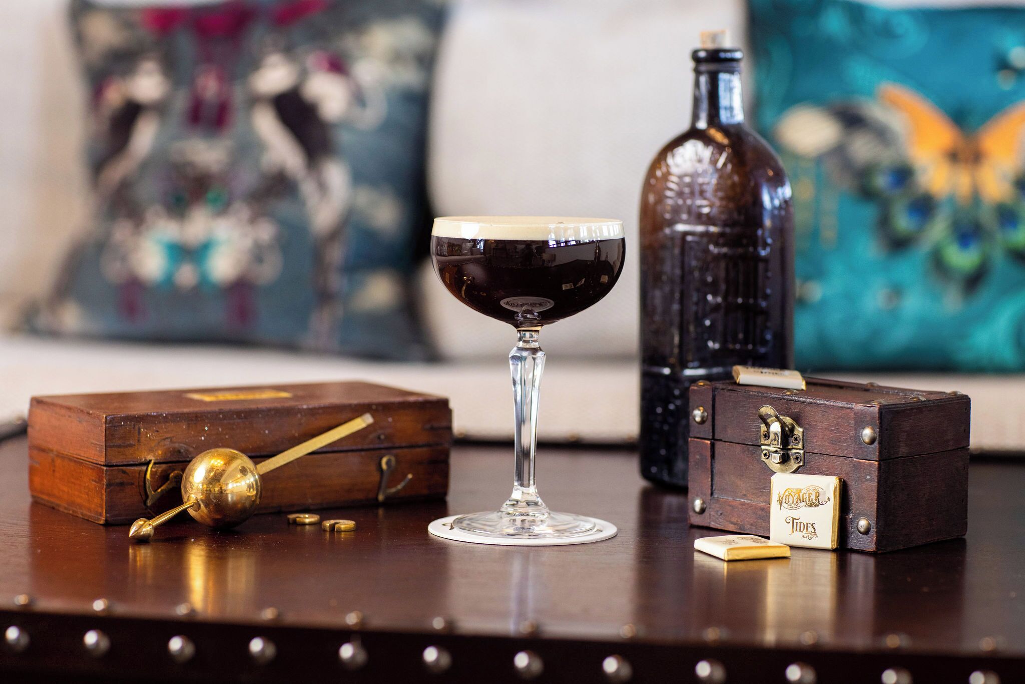 A wooden chest, a glass with a drink, and a bottle on a table.