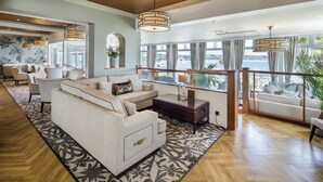A spacious living area with a large sofa, a coffee table, and a view of the sea. - Somerville Hotel (St. Brelade)