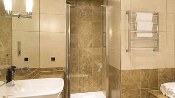 A modern bathroom with a bathtub, toilet, and shower.
