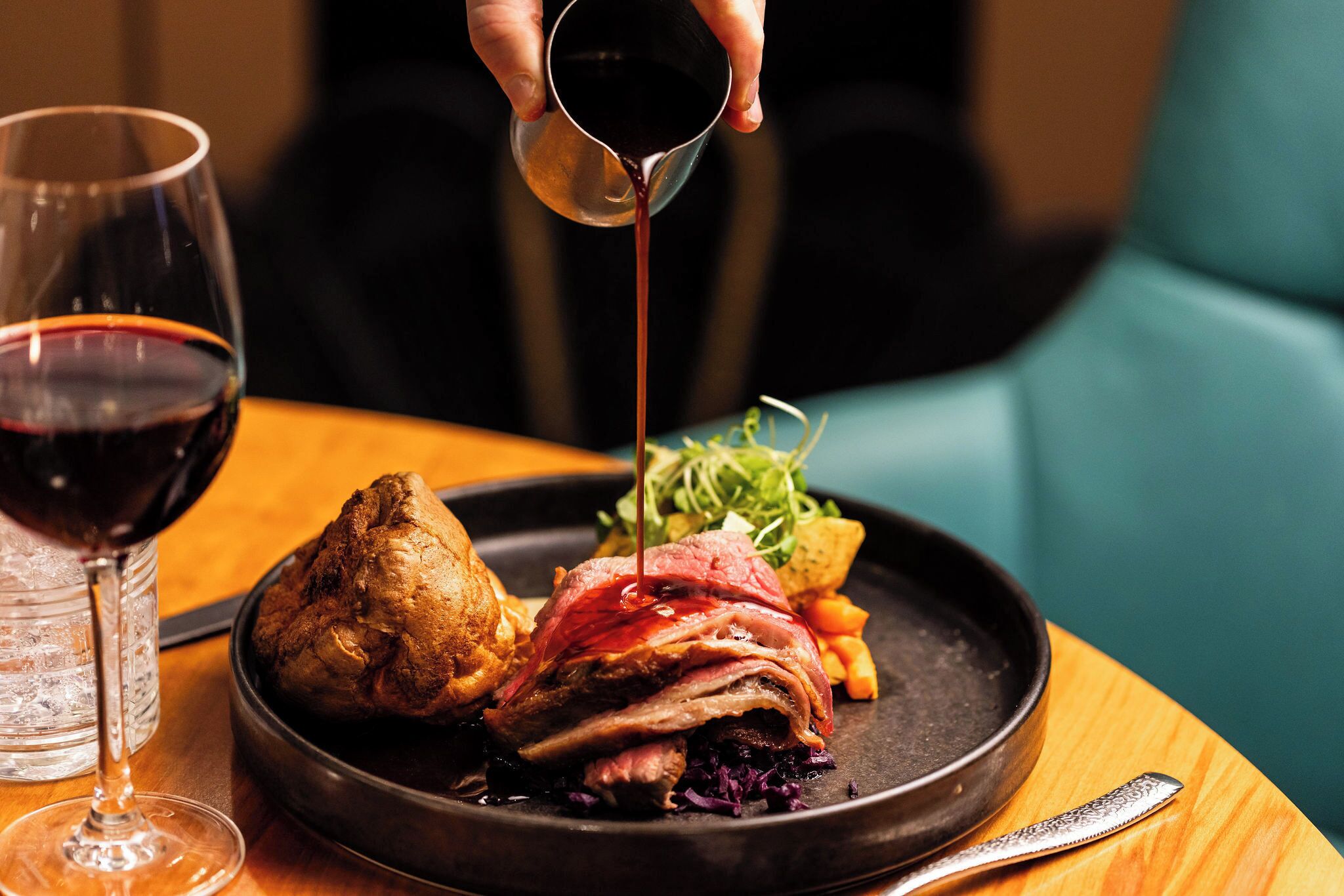 A plate of food with a glass of red wine and a bowl of salad.
