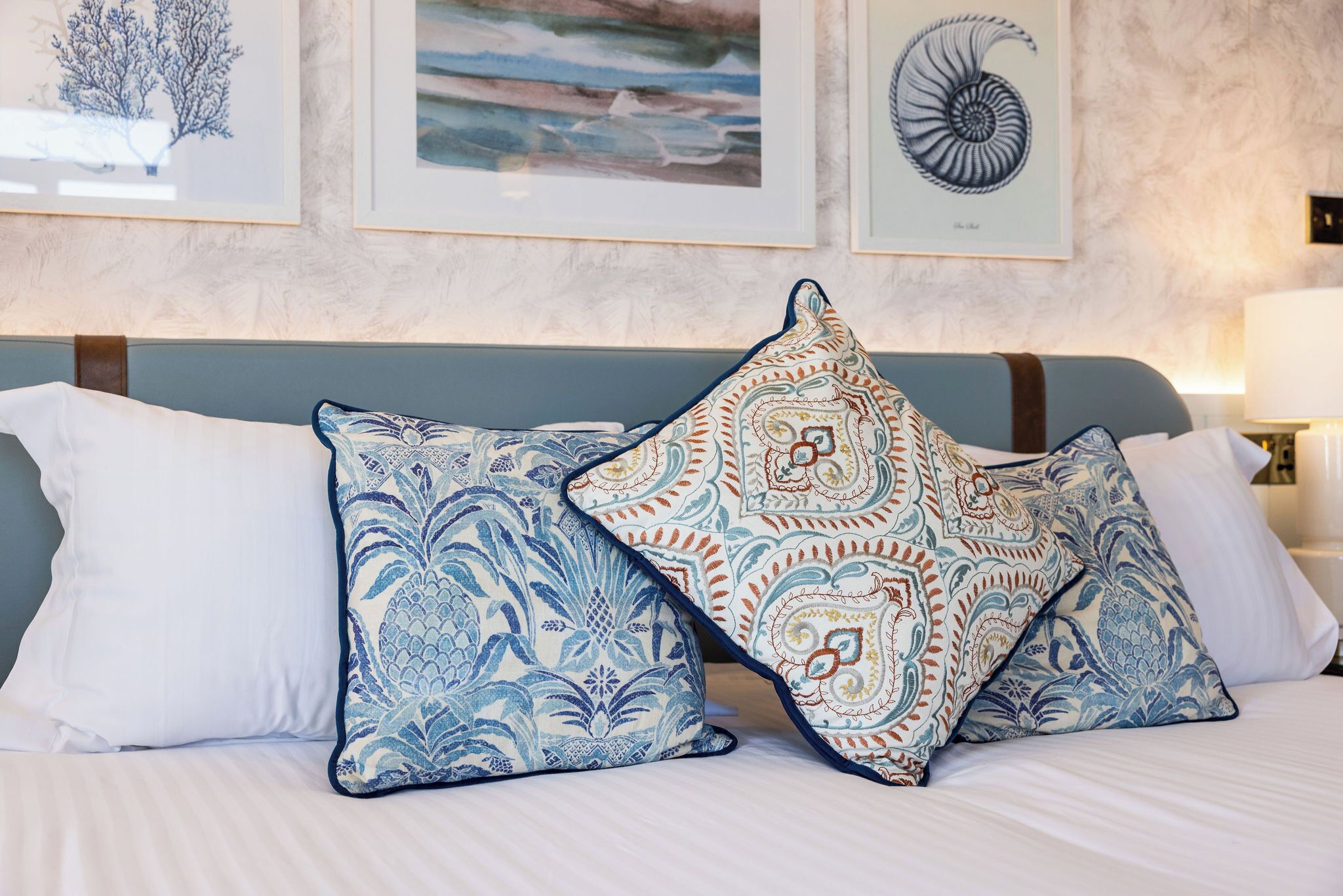 Ein Bett mit zwei gemusterten Kissen und einem gerahmten Kunstwerk darüber.