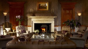A traditional living room with a fireplace, comfortable seating, and decorative elements. - Brockencote Hall Hotel (Kidderminster)