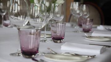 Ein gedeckter Tisch für einen festlichen Anlass mit mehreren Weingläsern und einer violetten Glasvase als Mittelstück.