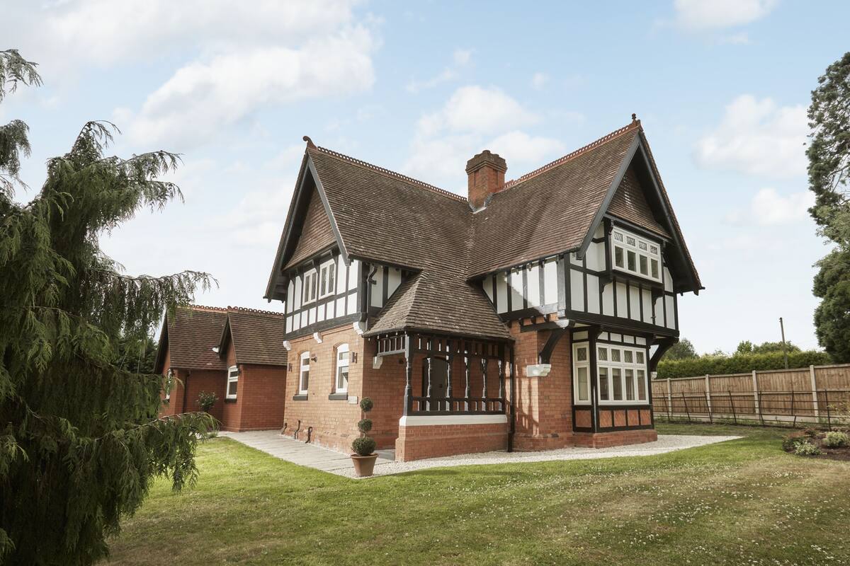 A Tudor-style house with a symmetrical facade, steeply pitched gable roofs, and a brick exterior.