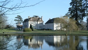 A large, stately building with a symmetrical facade, a manicured lawn, and a calm pond reflecting the structure. - Brockencote Hall Hotel (Kidderminster)