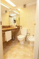 Un baño moderno con inodoro, lavabo y espejo.