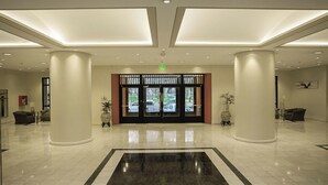 A spacious lobby with a large black and white rug, two large columns, and a view of the outside through the glass doors. - Austral Hotel (Comodoro Rivadavia)