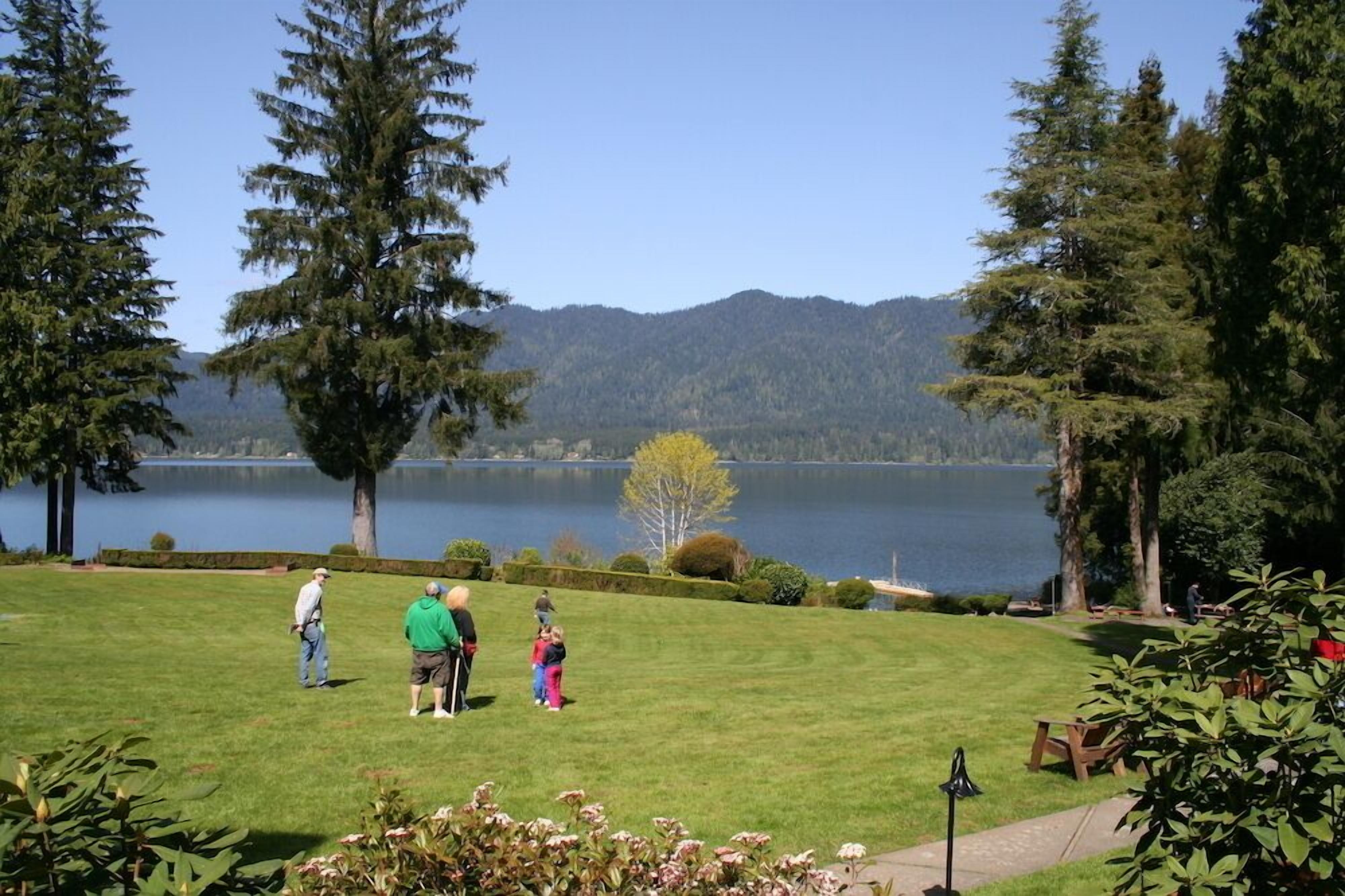 A grassy area with a lake and mountains in the background.