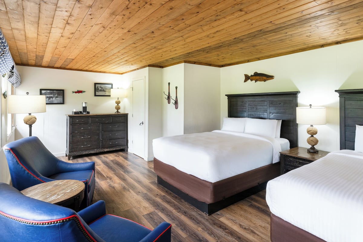 Une chambre d’hôtel avec un plafond en bois, un grand lit, un bureau, une chaise et une commode.