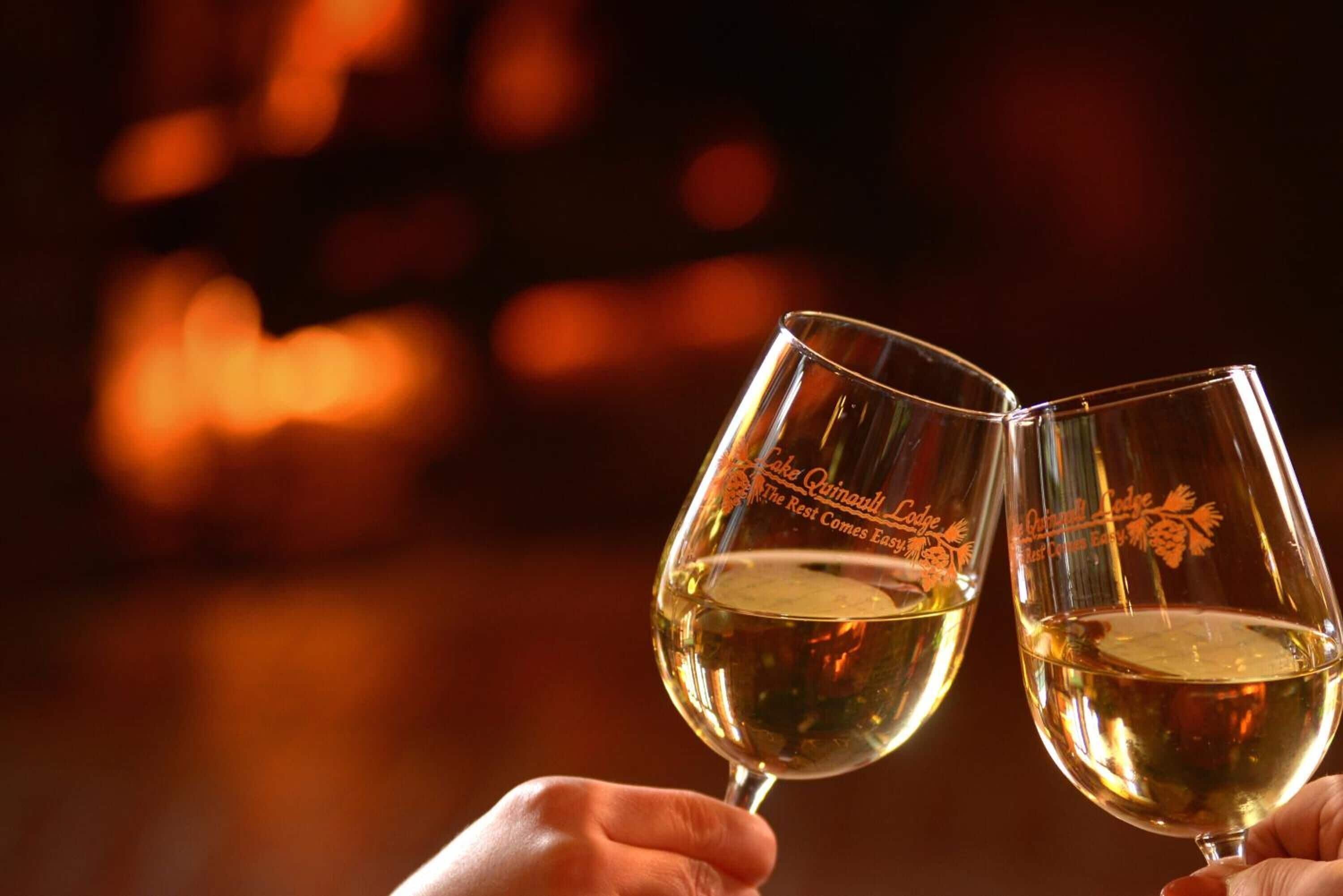 Two wine glasses with a logo, held by hands.