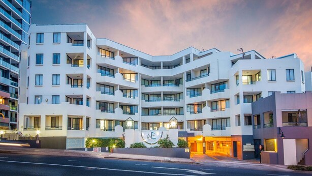 A multi-story hotel with a modern design, featuring balconies, large windows, and a well-lit entrance. - West End Central Apartments (South Brisbane)