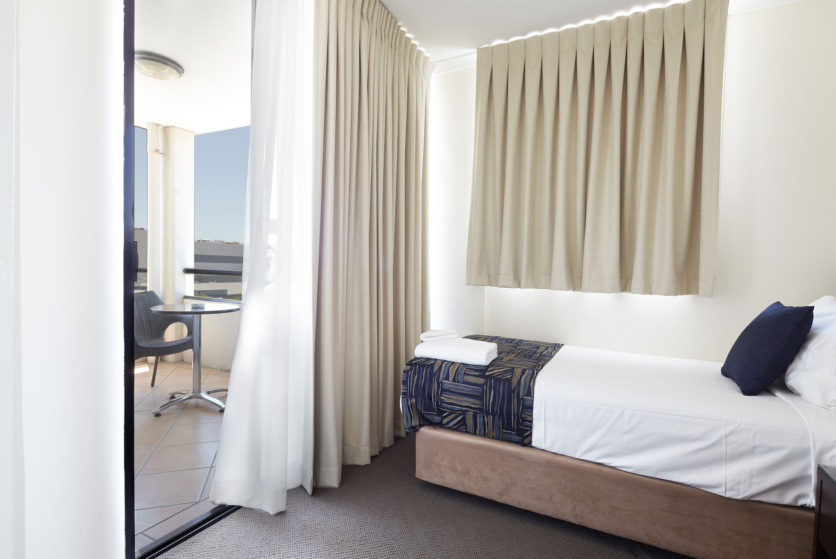 A hotel room with a bed, a small table, and a chair.