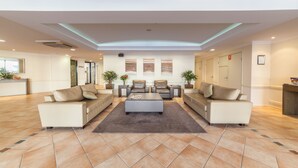 A spacious lobby with a central seating area, a reception desk, and a view of the hallway. - West End Central Apartments (South Brisbane)