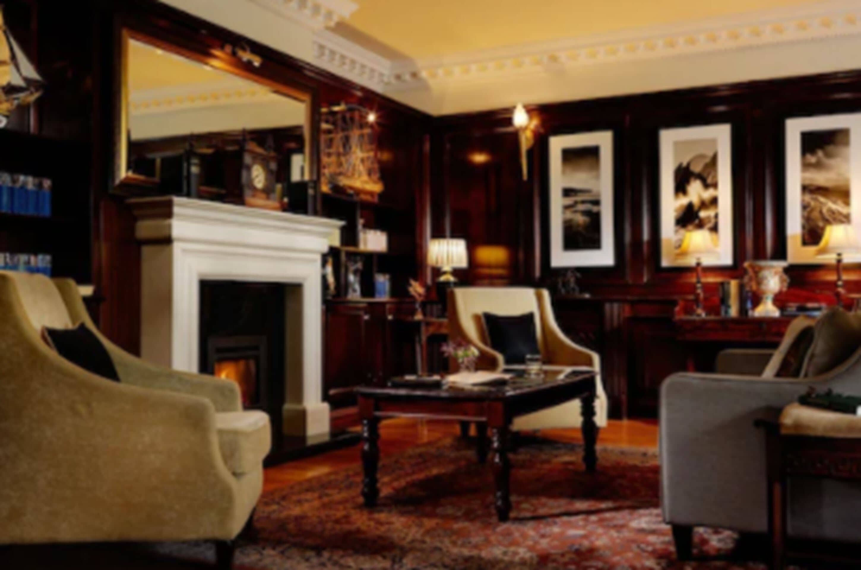 A traditional room with a fireplace, multiple armchairs, a coffee table, and framed artwork on the walls.
