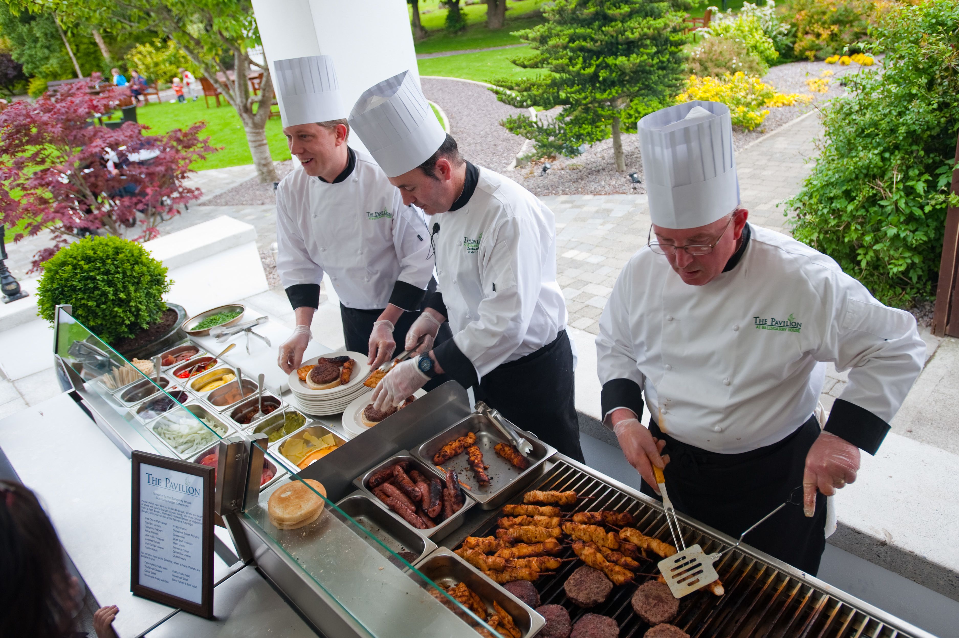 Chefs preparing food outdoors with a buffet display.