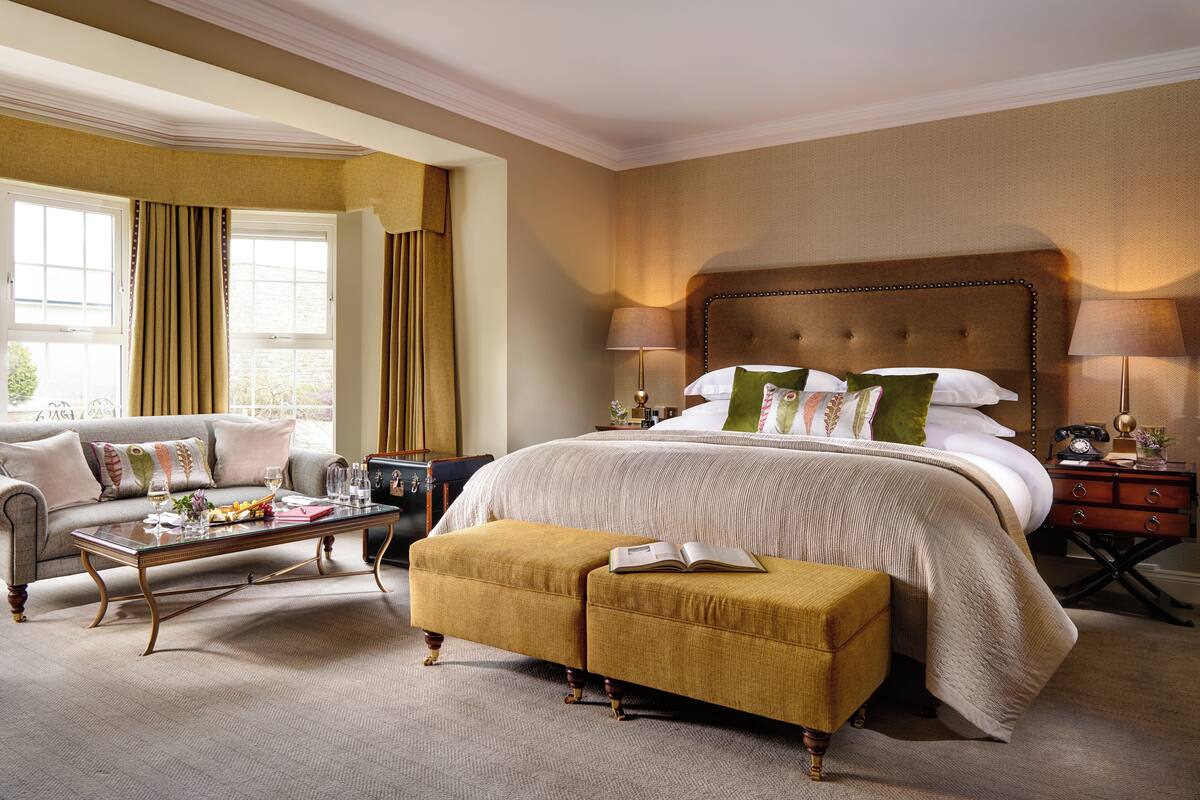 Ein Hotelzimmer mit einem großen Bett, einem Sofa, einem Couchtisch und einem Hocker.