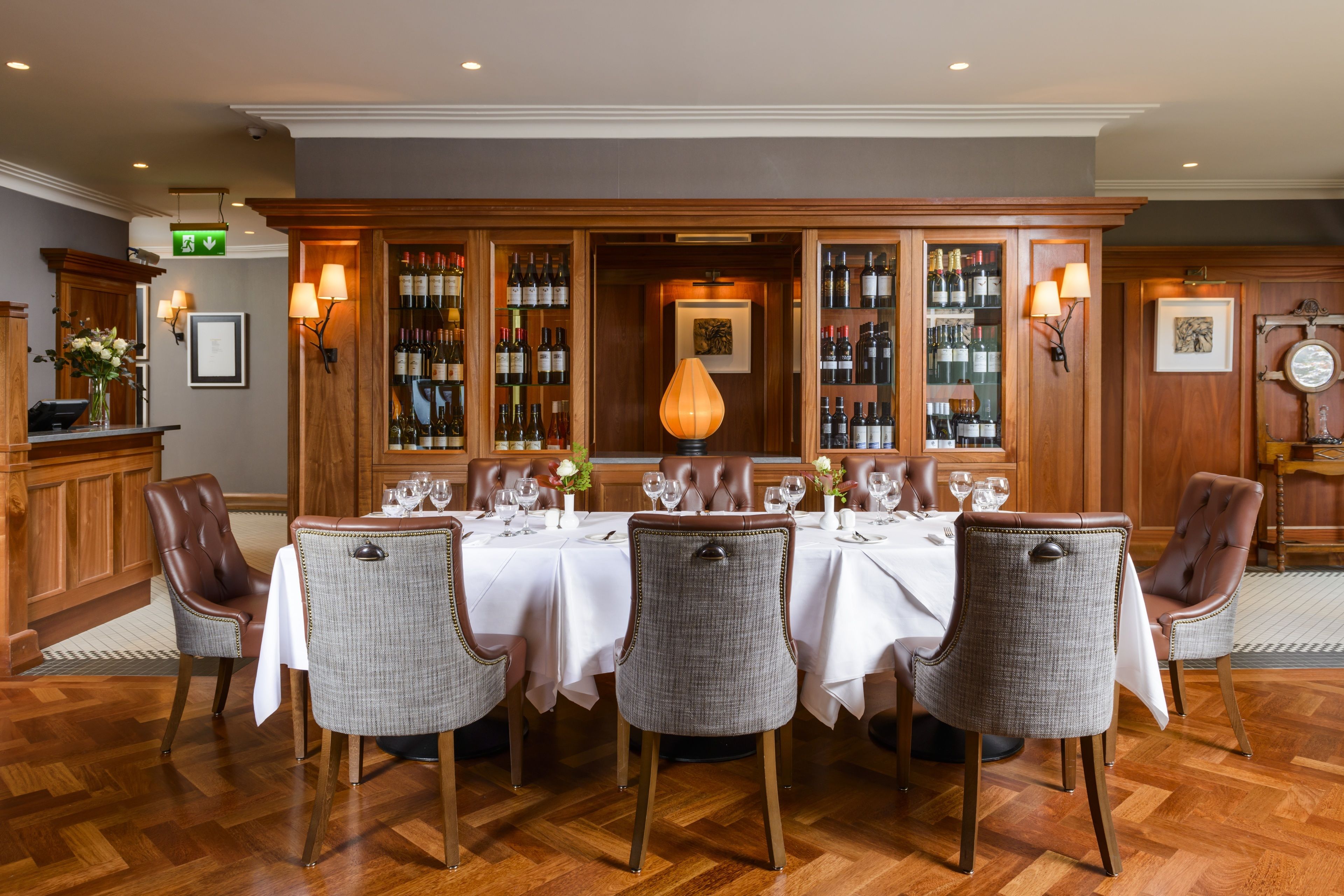 A dining area with a long table set for six, surrounded by upholstered chairs.