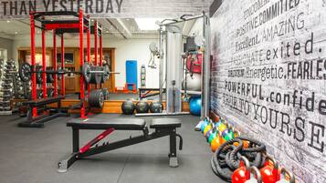Uma academia com equipamentos de musculação, bolas de exercício e frases motivacionais nas paredes.