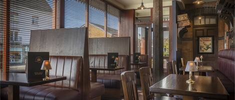 L'intérieur d'un restaurant avec des banquettes, des tables et des luminaires suspendus.
