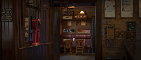 A cozy interior with a wooden bench, a table with chairs, and a vintage red fire alarm.