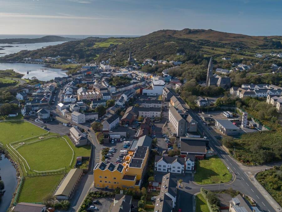An aerial view of a town with a mix of residential and commercial buildings, a prominent church, and a river.