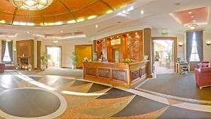 Un hall d’entrée spacieux avec un comptoir d’accueil, une cheminée et un grand sol orné de motifs.