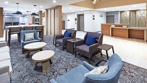 Un hall d’hôtel moderne comprenant un espace repas, des coins salon et un comptoir d’accueil.