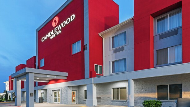 Un hôtel moderne à la façade rouge, avec de nombreux étages et un ciel dégagé.