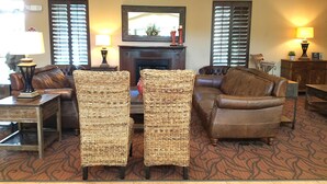A living room with a fireplace, leather sofas, wicker chairs, and two lamps. - Hawthorn Extended Stay by Wyndham Orlando (Orlando)