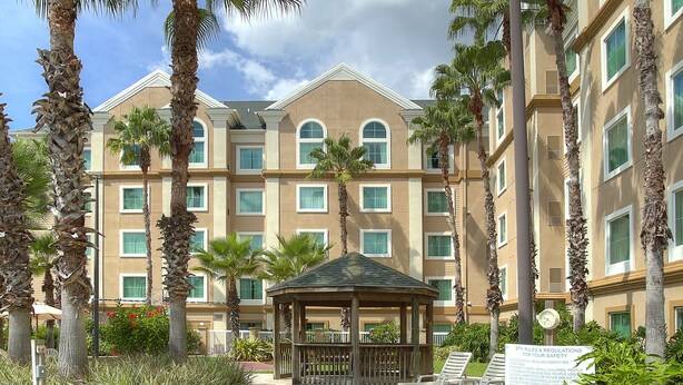A hotel with a pool area, palm trees, and a gazebo. - Hawthorn Extended Stay by Wyndham Orlando (Orlando)