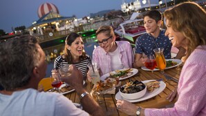 A group of people dining at a waterfront restaurant with a view of boats and a hot air balloon in the background. - Hawthorn Extended Stay by Wyndham Orlando (Orlando)