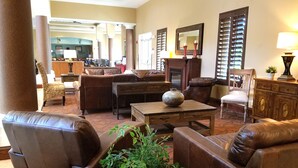 A spacious living area with leather sofas, a wooden coffee table, and a large vase. There is a dining area in the background with a wooden table and chairs. - Hawthorn Extended Stay by Wyndham Orlando (Orlando)
