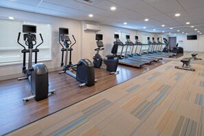 A gym with various exercise equipment, including treadmills and stationary bikes, arranged in rows.