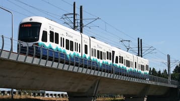 A white train with blue wave patterns on a bridge.