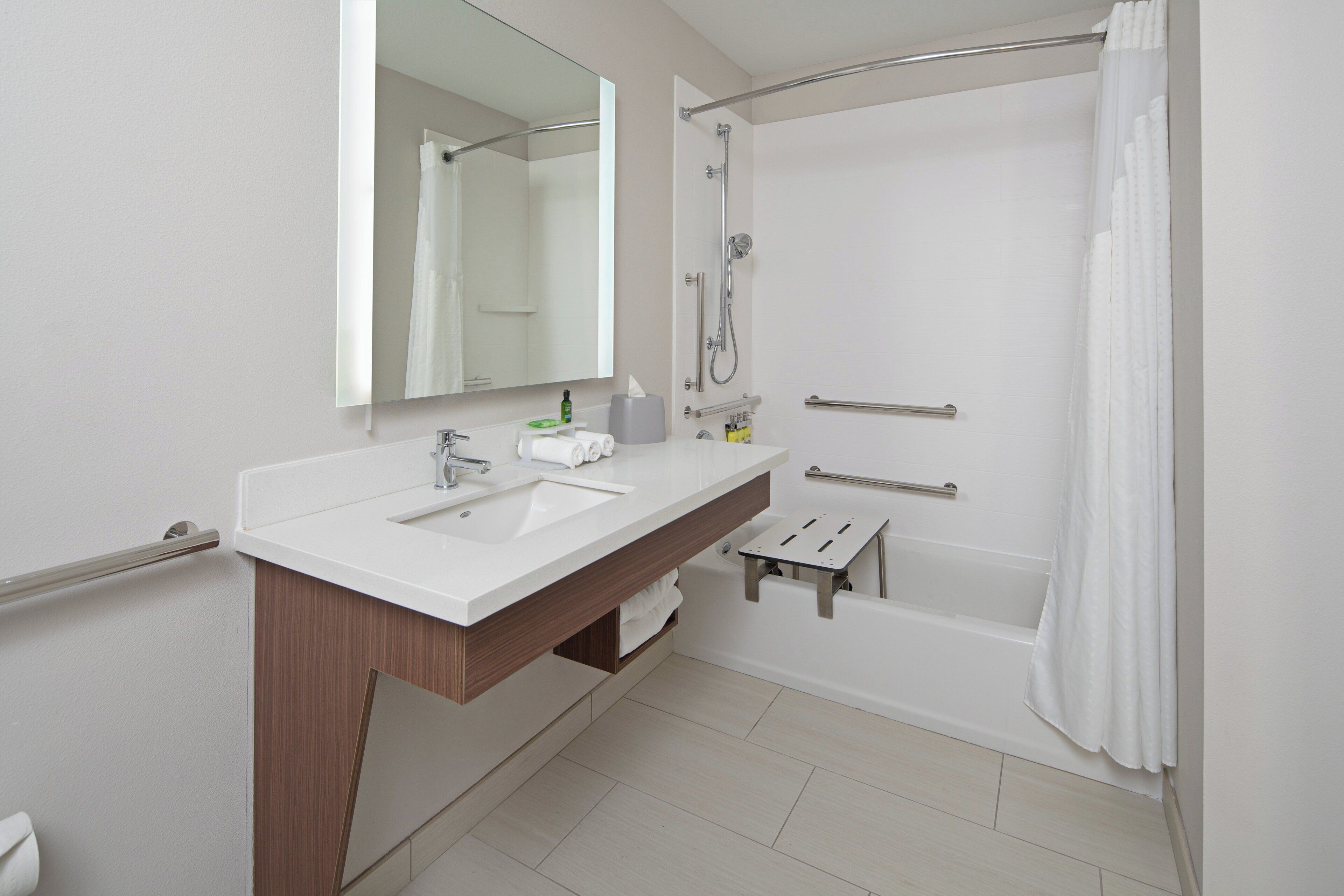 A modern bathroom with a double sink vanity, a shower with a glass door, and a mirror above the vanity.