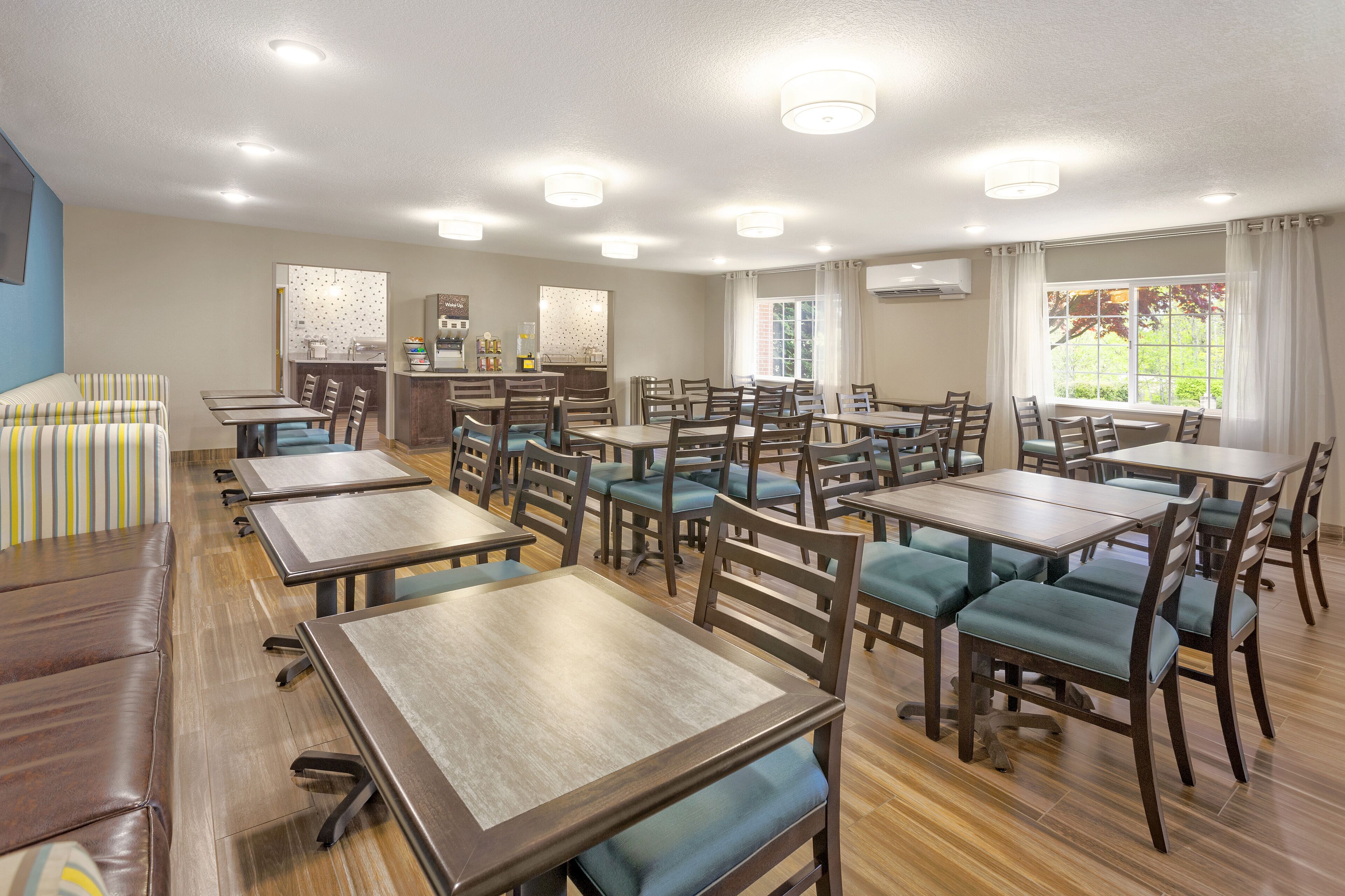 A dining area with multiple tables and chairs, a sofa, and a counter with a menu.