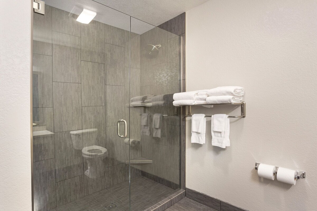 A modern bathroom with a glass-enclosed shower, a toilet, and a towel rack with towels.
