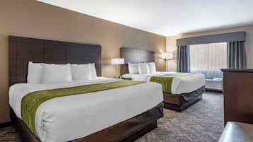 Ein Hotelzimmer mit zwei Betten, einem großen Fenster mit Vorhängen und einem Teppichboden.