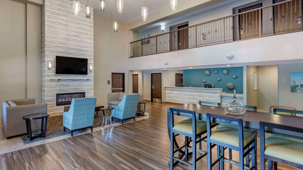 A spacious lobby with a high ceiling, a fireplace, seating area, and a bar with stools.
