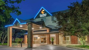 A Comfort Inn & Suites with a prominent neon sign, a covered entrance, and a brick facade.